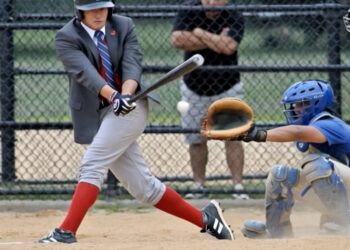 Businessman in suit striking out at baseball plate with umpire making dramatic out sign, illustrating fatal flaw in strong salespeople